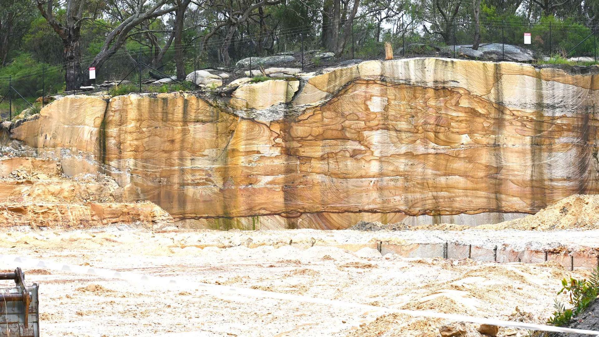 A Large Rock Wall Is Surrounded By Trees And Dirt – Port Pirie, SA - Flinders Earthmoving & Blue Metal Supplies