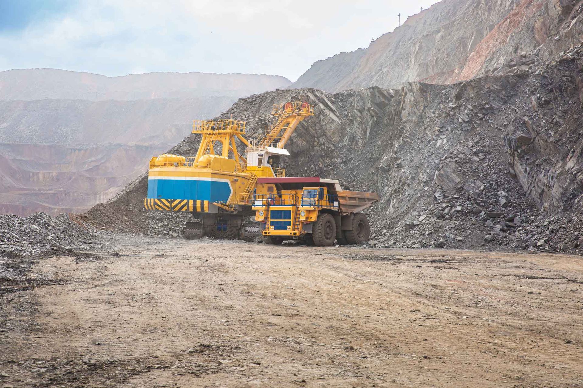 A Large Yellow Excavator Is Loading A Dump Truck In A Coal Mine – Port Pirie, SA - Flinders Earthmoving & Blue Metal Supplies