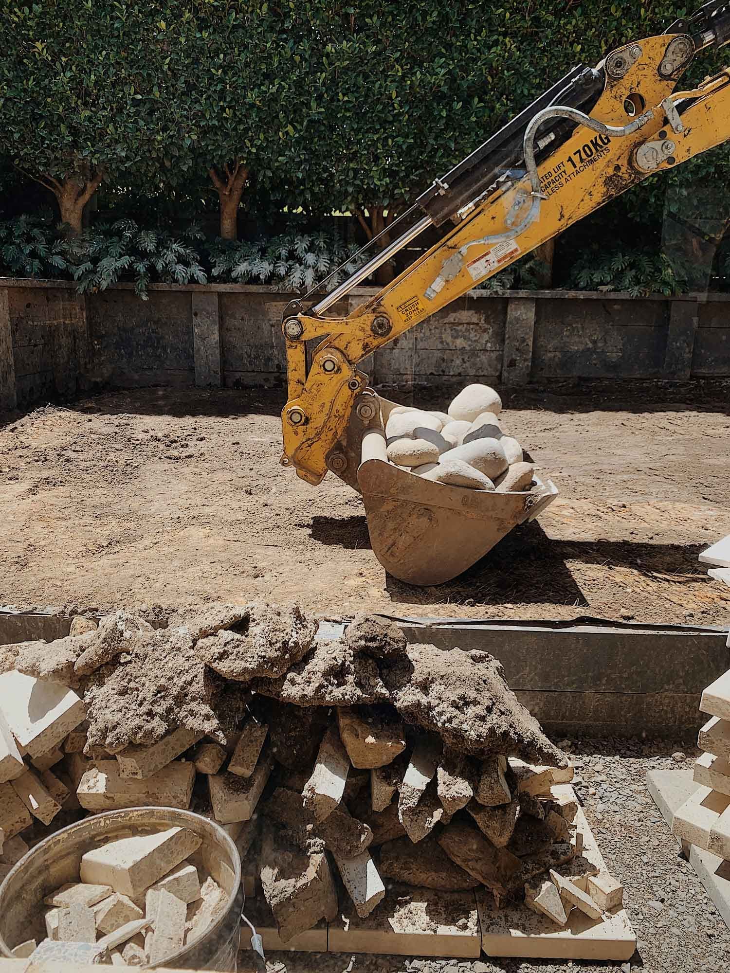 A Yellow Excavator Is Loading A Bucket Of Rocks Into A Pile Of Rocks – Port Pirie, SA - Flinders Earthmoving & Blue Metal Supplies