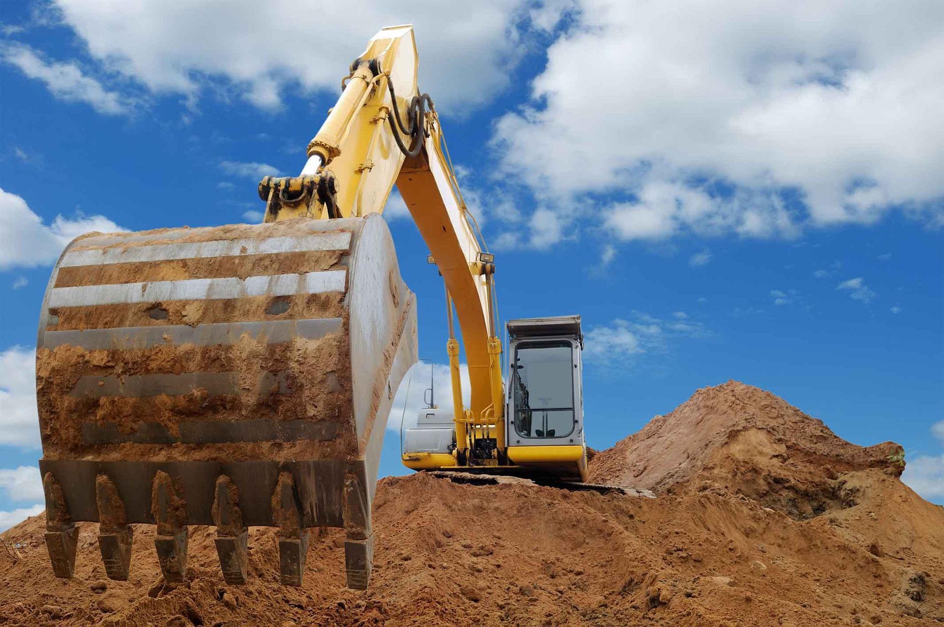 A Yellow Excavator Is Digging In A Pile Of Dirt – Port Pirie, SA - Flinders Earthmoving & Blue Metal Supplies