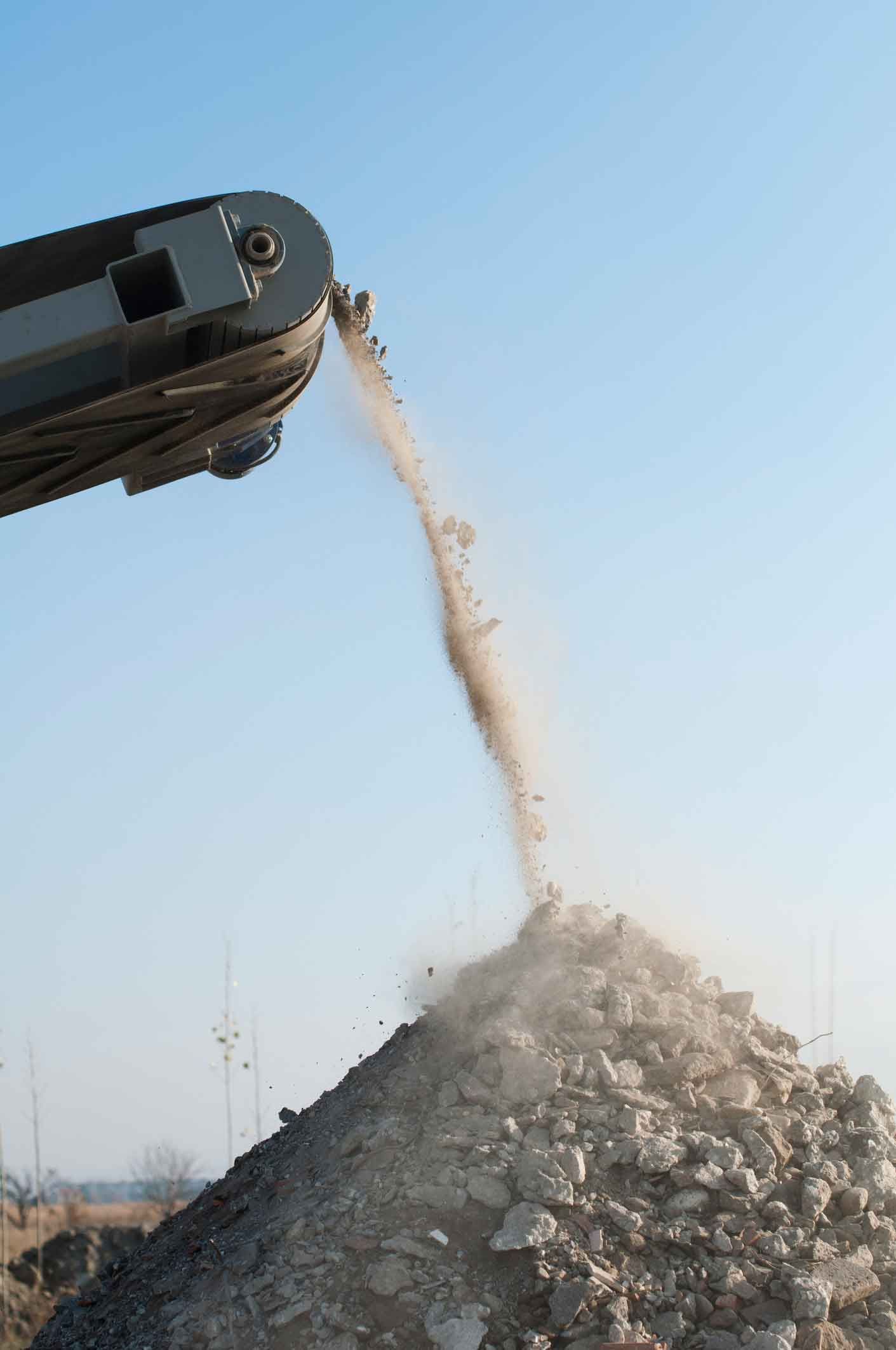 A Machine Is Pouring Dirt Into A Pile Of Rocks – Port Pirie, SA - Flinders Earthmoving & Blue Metal Supplies