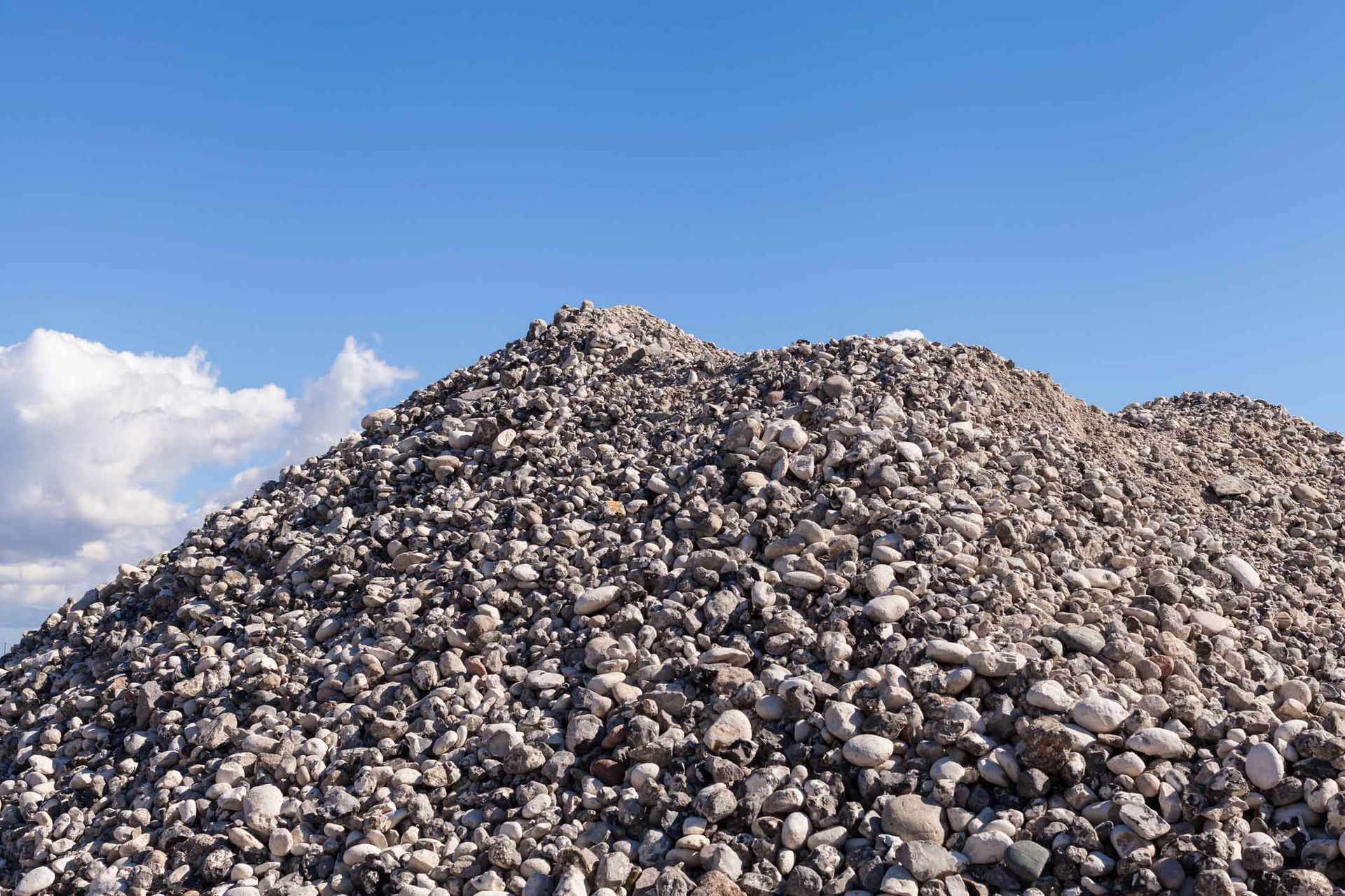 A Pile Of Rocks Against A Blue Sky With Clouds – Port Pirie, SA - Flinders Earthmoving & Blue Metal Supplies