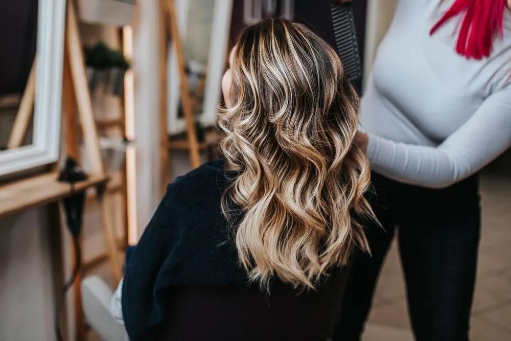 A Woman is Getting Her Hair Done by a Hairdresser in a Salon — Southside Hair & Beauty Design In South Tamworth, NSW