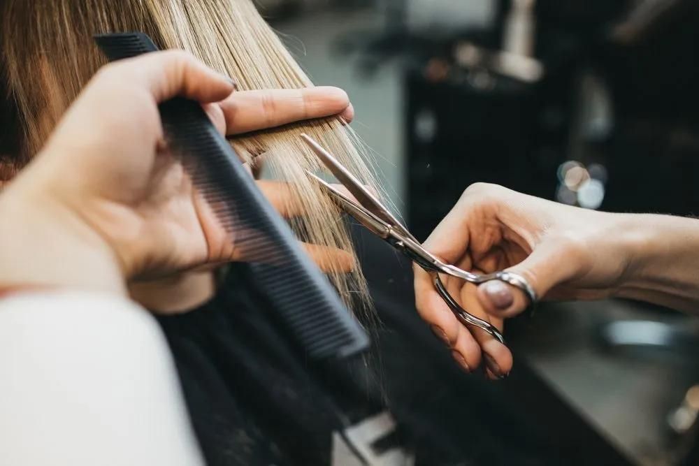 A Woman is Getting Her Hair Cut by a Hairdresser in a Salon — Southside Hair & Beauty Design In South Tamworth, NSW