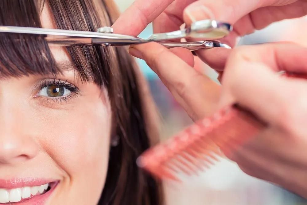 A Woman is Getting Her Hair Cut by a Hairdresser — Southside Hair & Beauty Design In South Tamworth, NSW