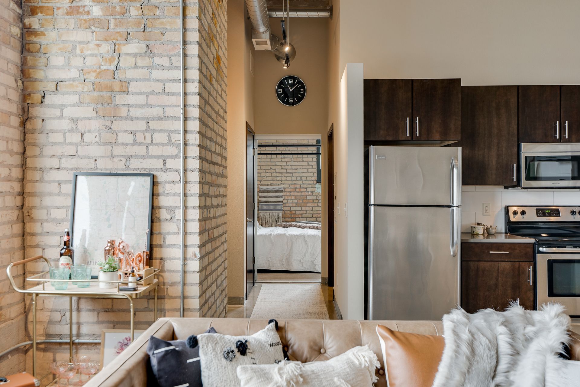 A large open floor plan showcasing a decorated living area and modern kitchen with dark cabinets and stainless steel appliances.