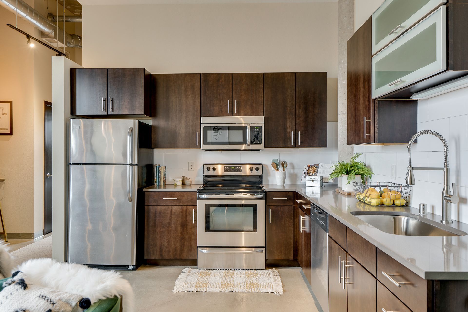 A modern kitchen featuring dark wood cabinets, stainless steel appliances, and a light gray countertop.