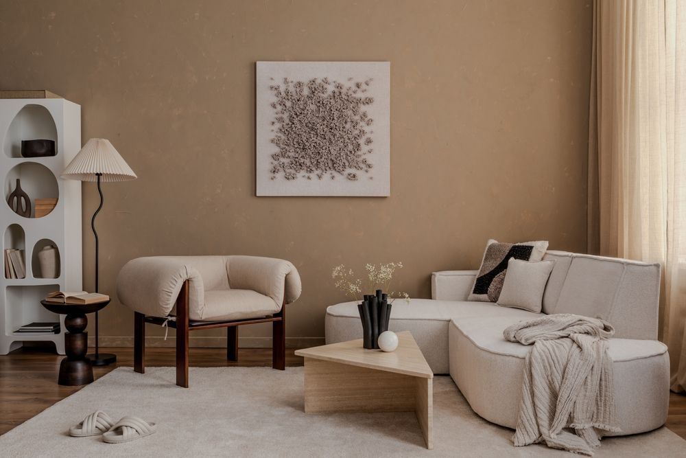 Beige living room with sofa, armchair, coffee table, art, and rug.