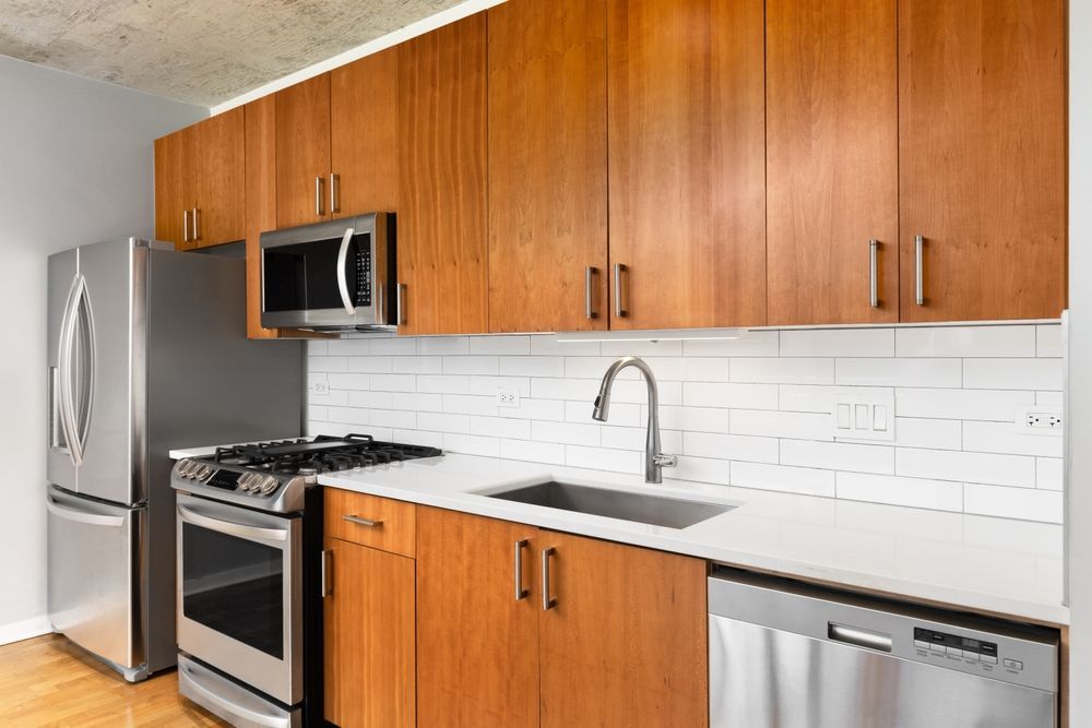 Kitchen with wood cabinets, stainless steel appliances, white countertops, and a subway tile backsplash.