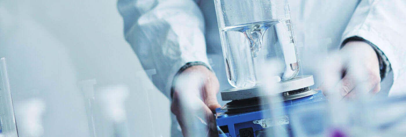 Un científico está vertiendo líquido en un vaso de precipitados en un laboratorio.