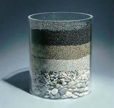 Un vaso lleno de diferentes tipos de rocas y arena.