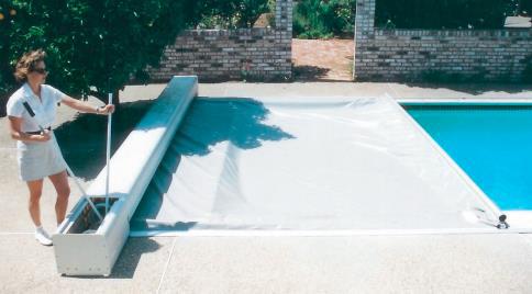 Una mujer está parada junto a una piscina con una cubierta.