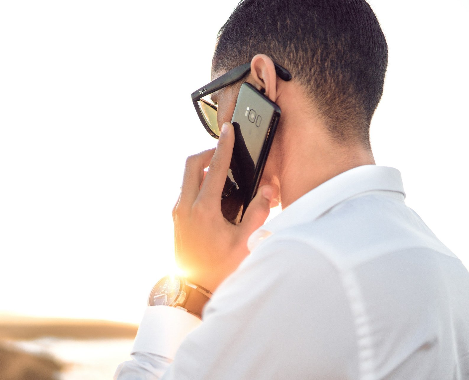 Un hombre que lleva gafas de sol está hablando por un teléfono celular.