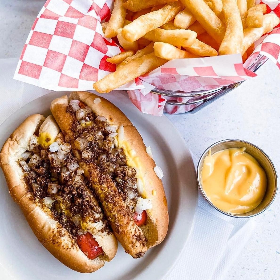 Two New Way Lunch hot dogs on a plate next to a basket of french fries