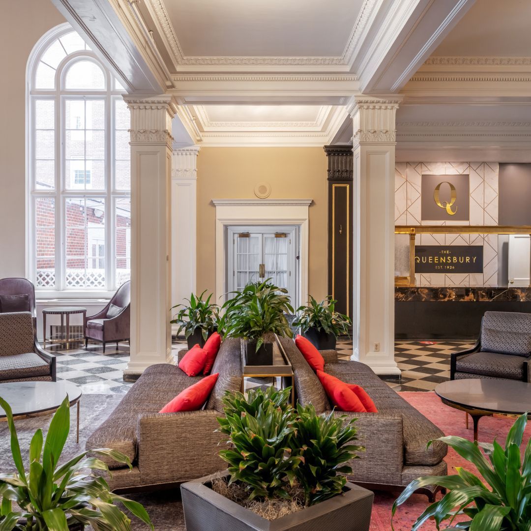 The hotel lobby at the Queensbury Hotel with a couch and chairs and plants