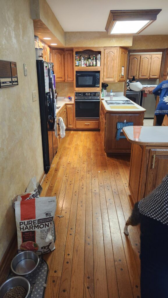 A kitchen with wood cabinets and hardwood flooring