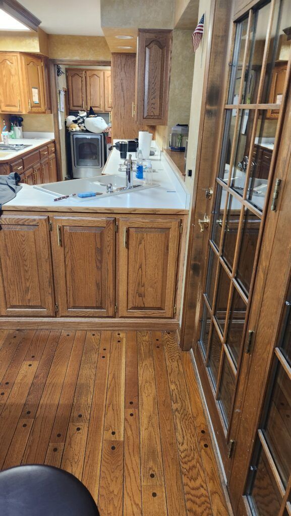 A kitchen with wooden cabinets and hardwood floors.