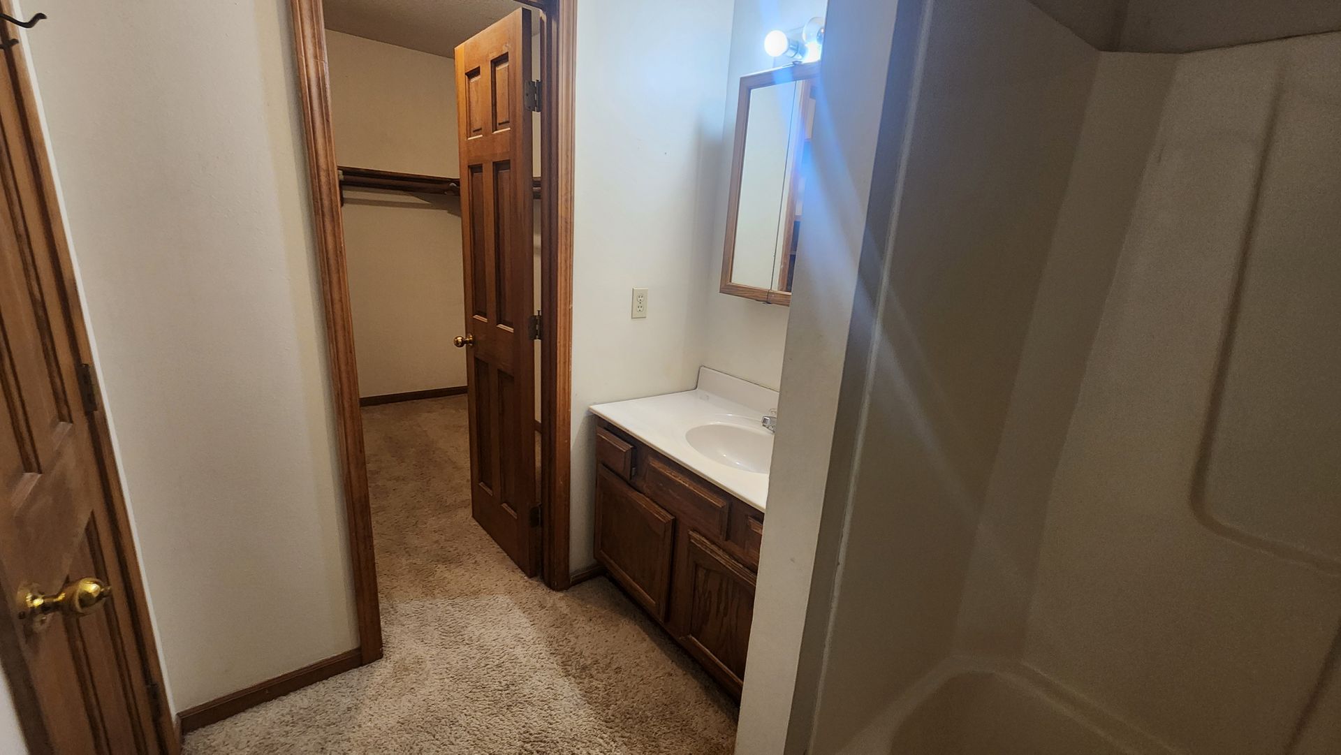 Bathroom with a vanity, mirror, and tub. A closet door is open nearby.