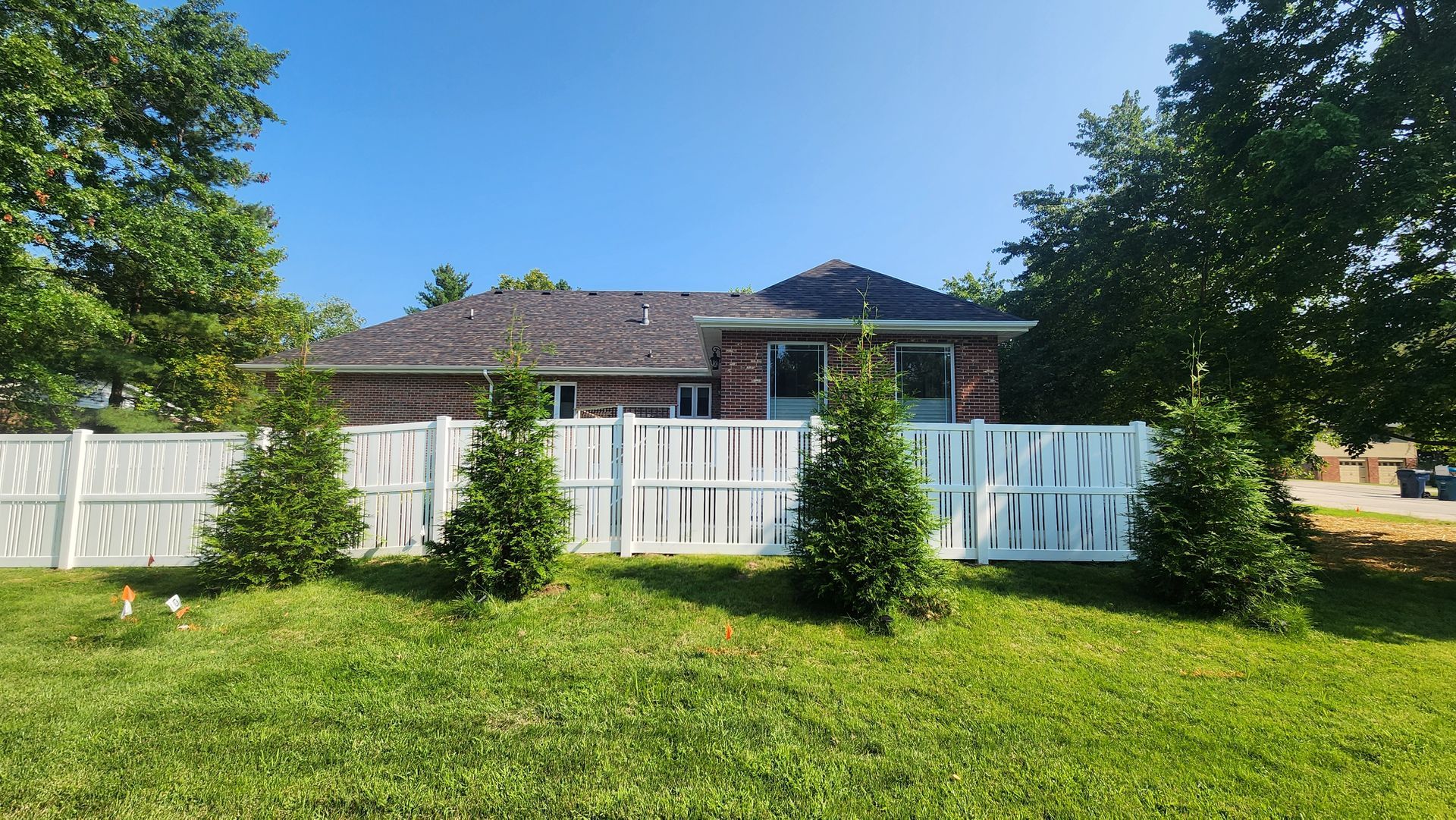 A house with a white fence and trees in front of it.