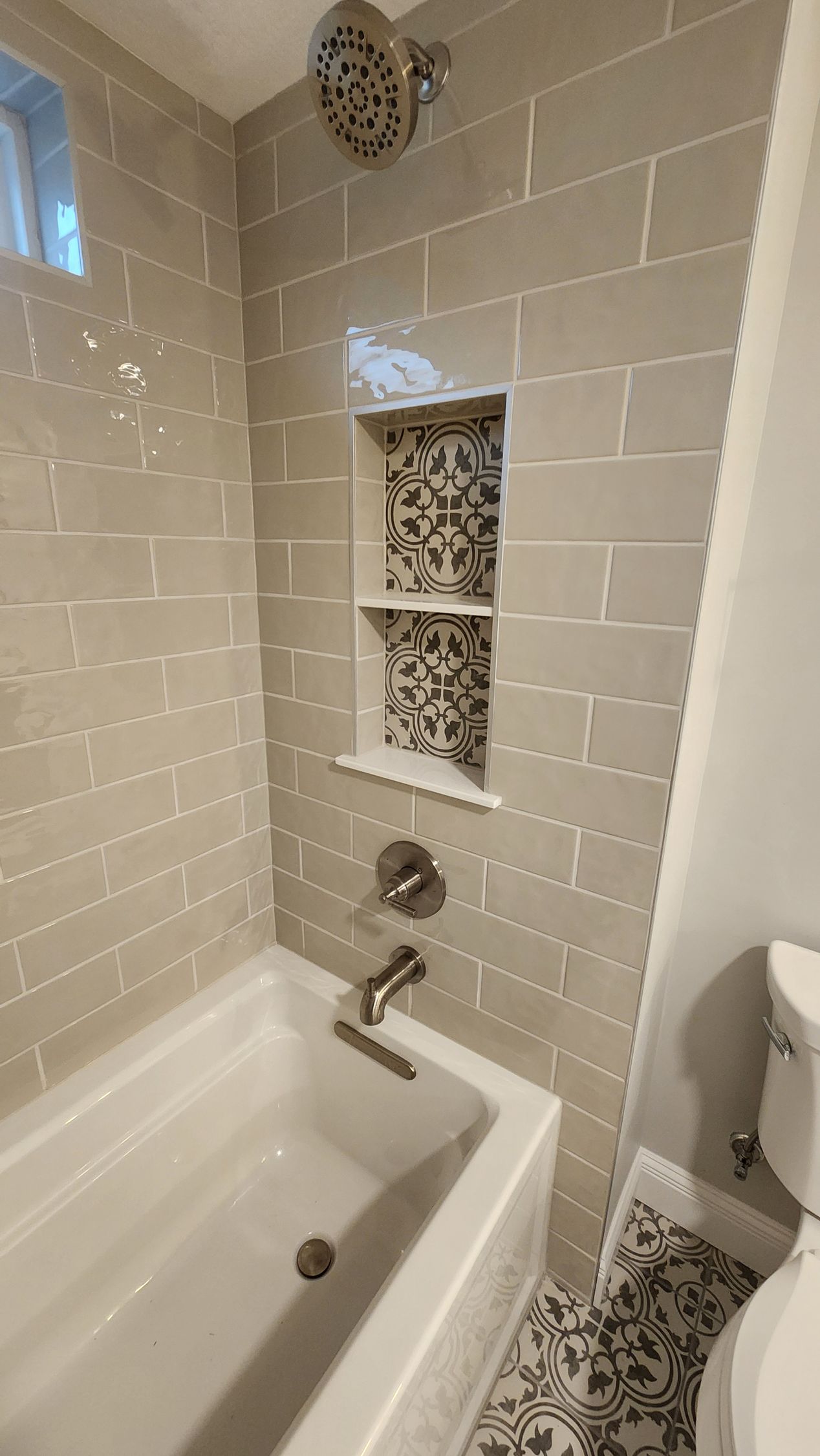 Bathroom with a white tub, tiled walls, and a recessed shelf.