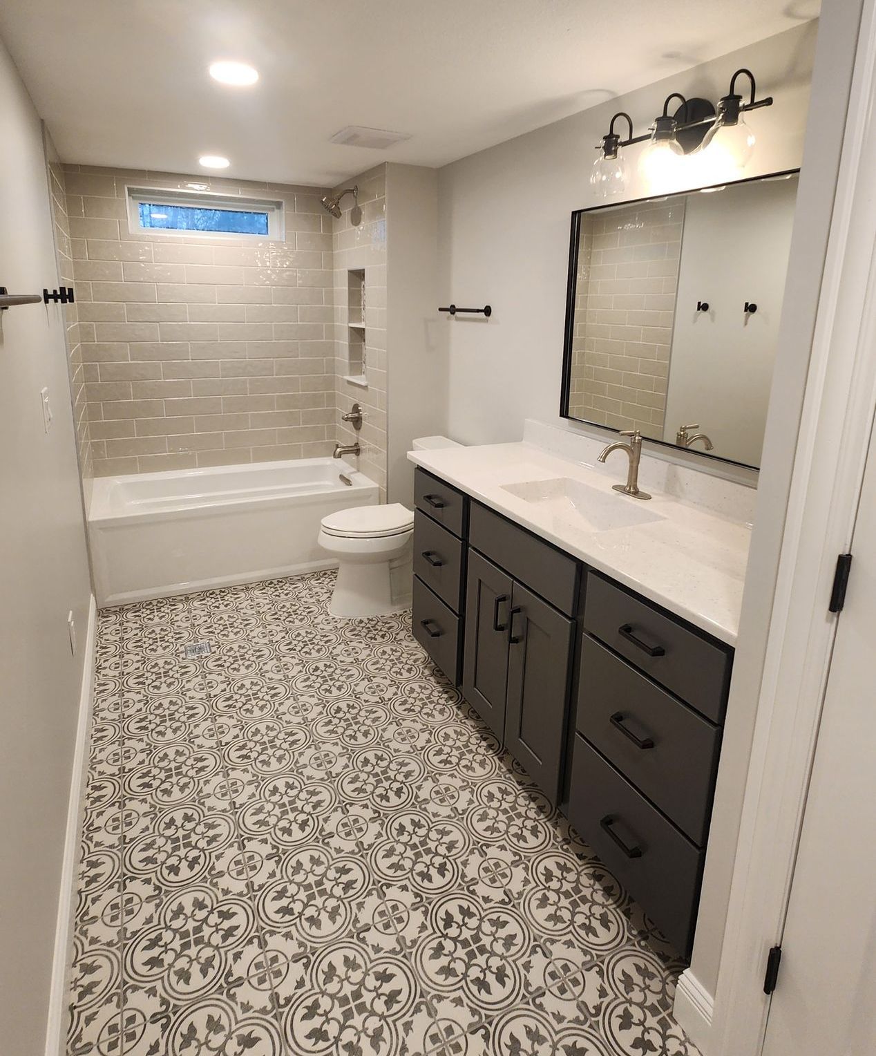 A bathroom with a walk in shower , sink , mirror and blue cabinets.
