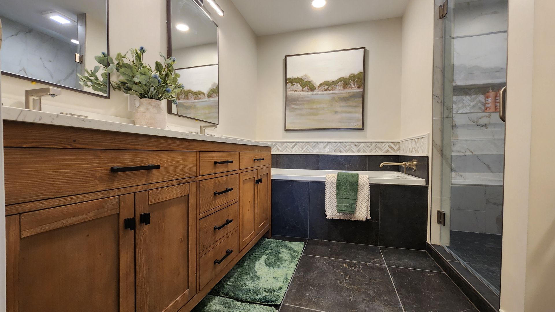 Bathroom with wooden vanity, artwork, a tub, and a walk-in shower.