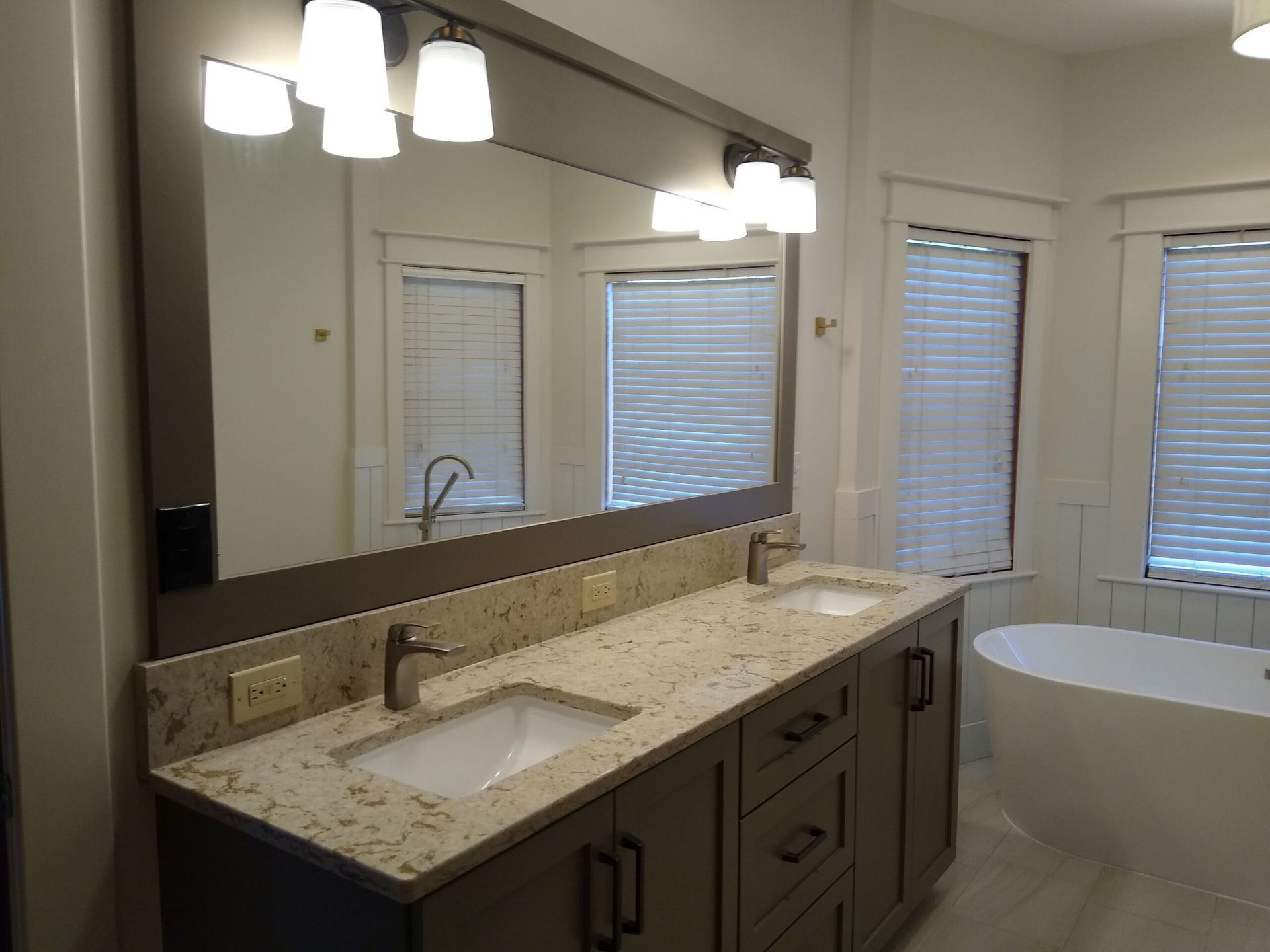 A bathroom with two sinks , a tub and a large mirror.