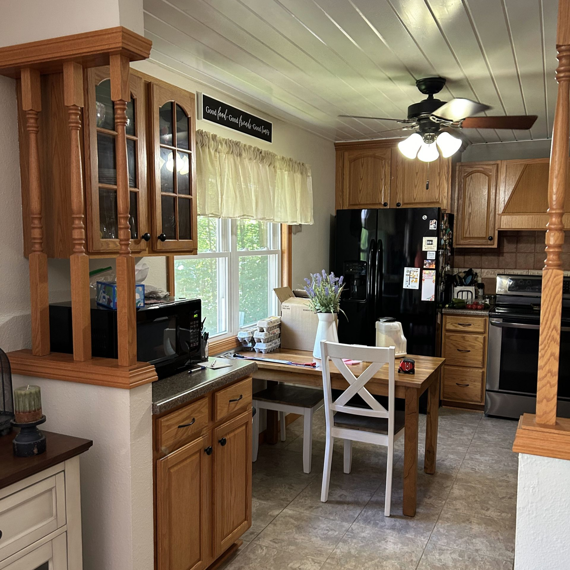 Kitchen with wooden cabinets, black appliances, and a table with chairs.