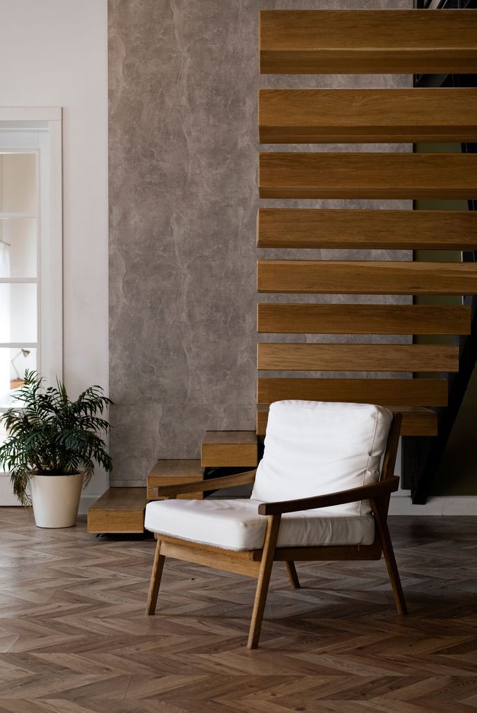 a chair is sitting in a living room next to a wooden staircase .