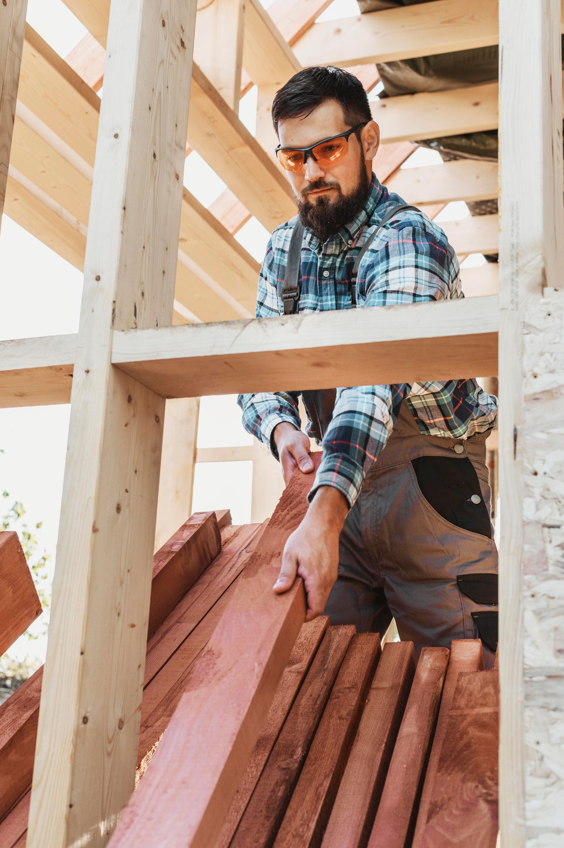 a man is standing next to a pile of wood .