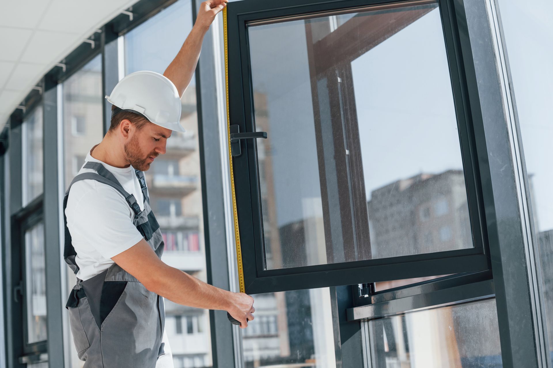 a man is measuring a window with a tape measure .