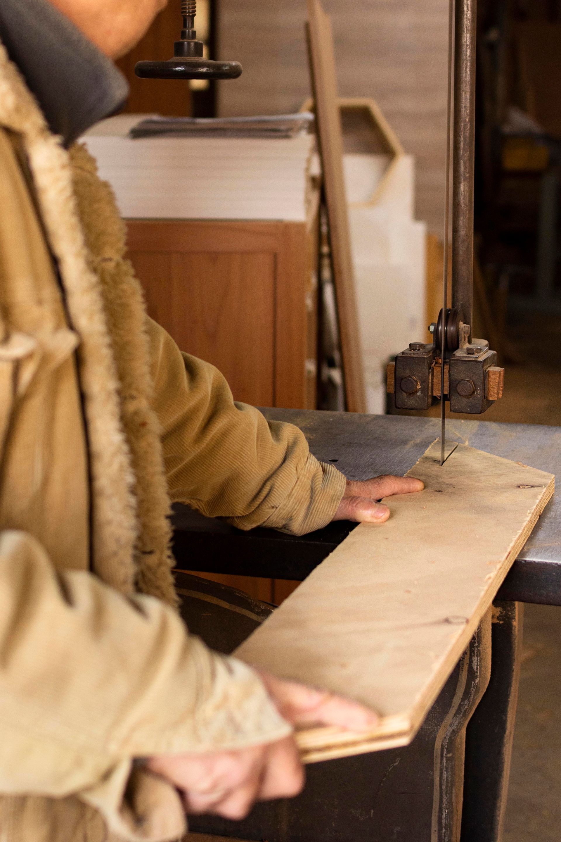 a man is cutting a piece of wood with a band saw .