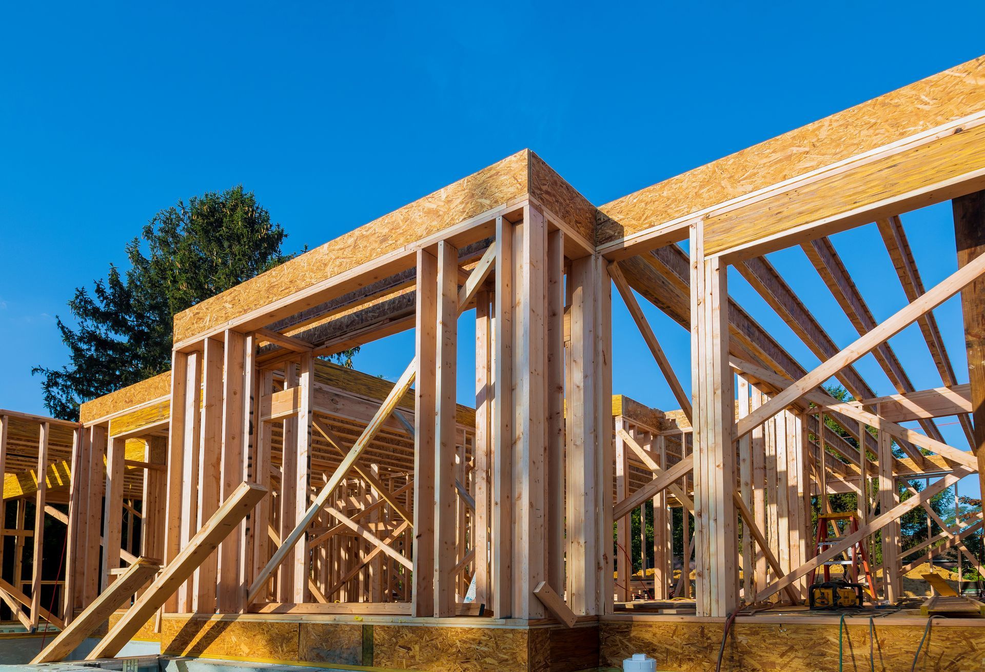 a house is being built with wooden beams and a blue sky in the background .