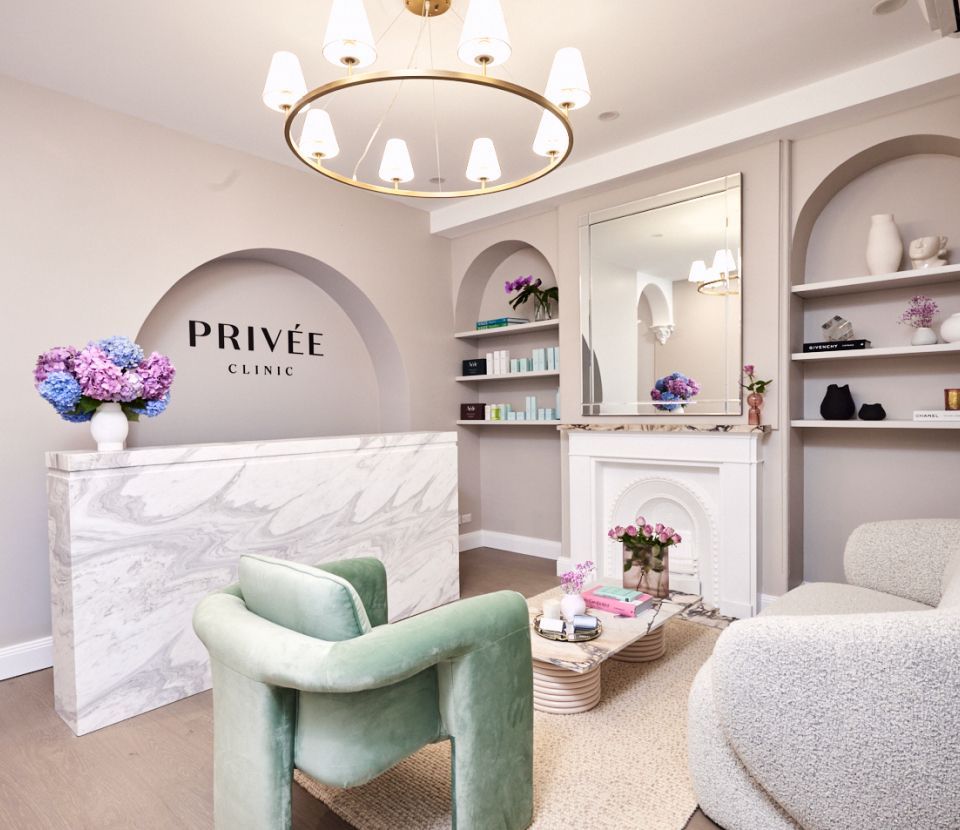 Elegant clinic reception area with marble desk, arch, and modern seating.
