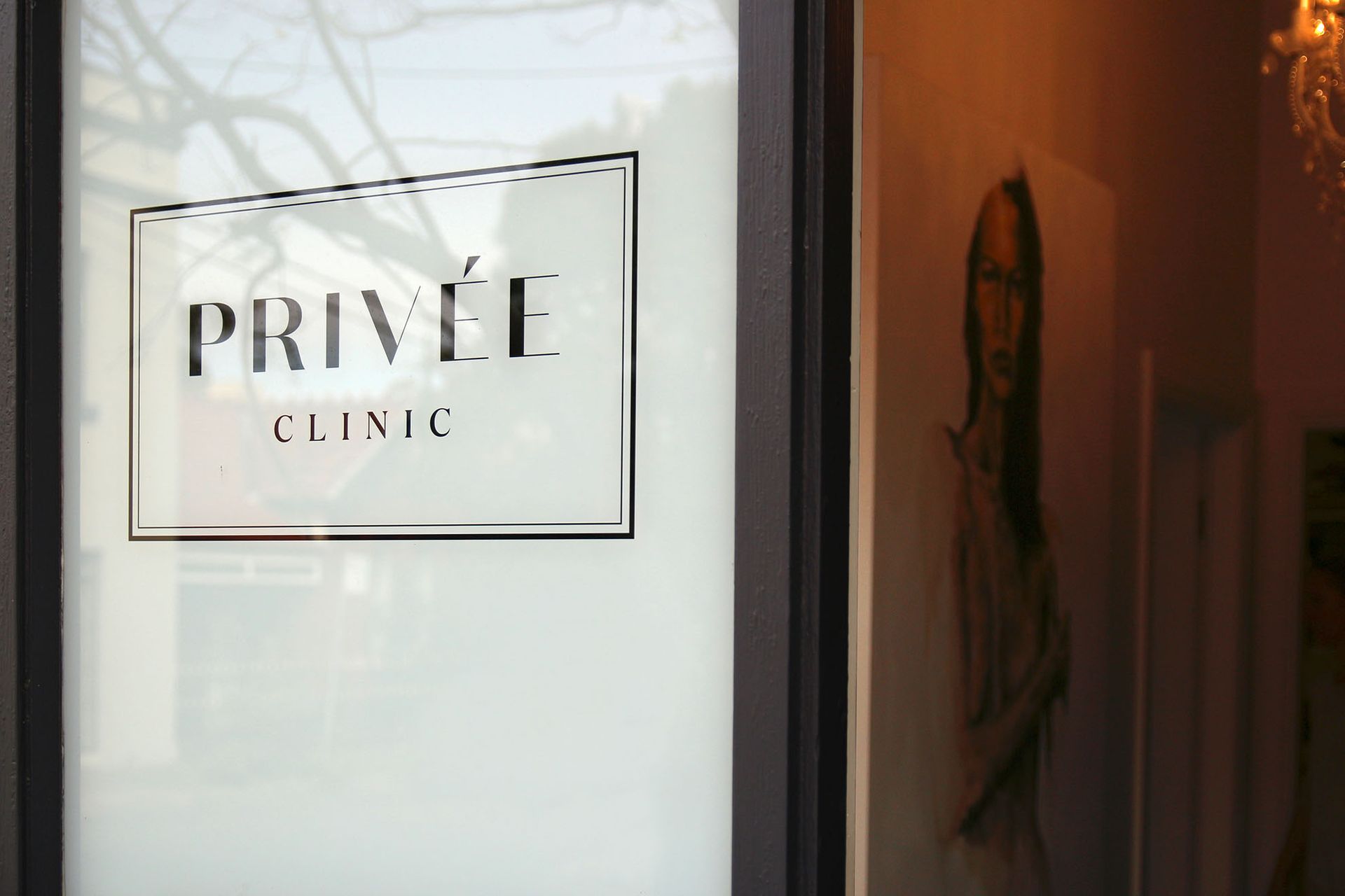 Signage for Privée Clinic on a frosted glass door, interior artwork visible.