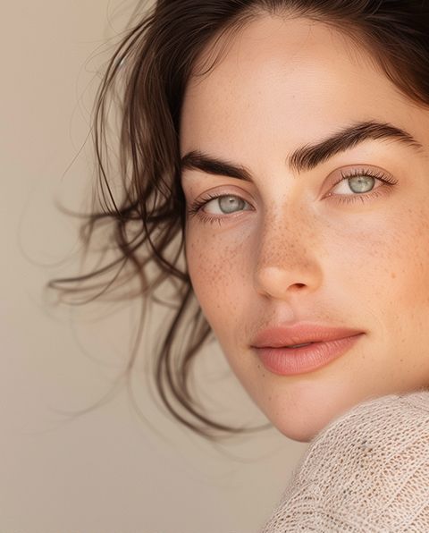 Woman with light skin, blue eyes, and freckles, looking towards the camera.