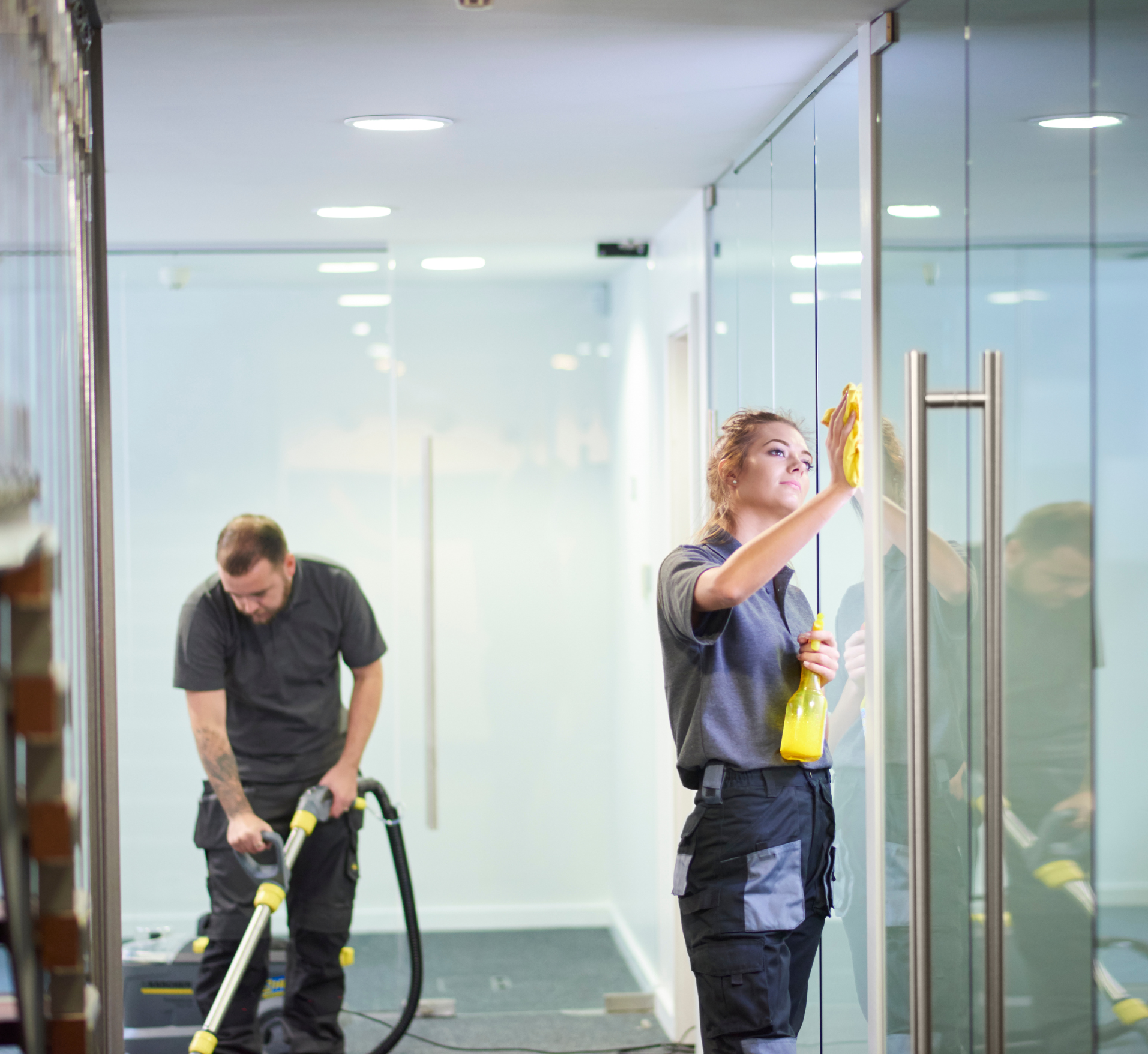 A man and a woman are cleaning the floor in a living room.