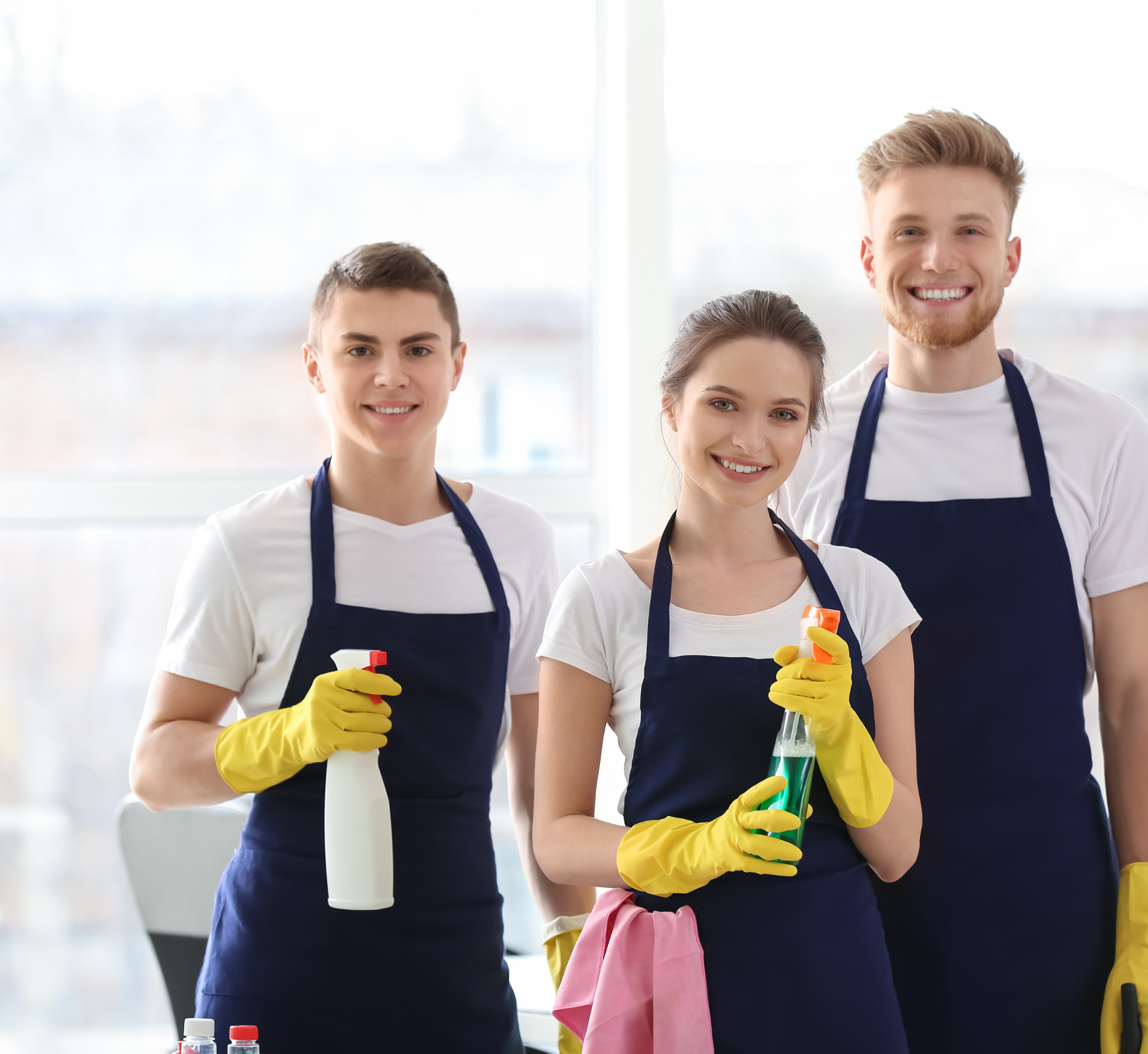 A man and two women are standing next to each other holding cleaning supplies.