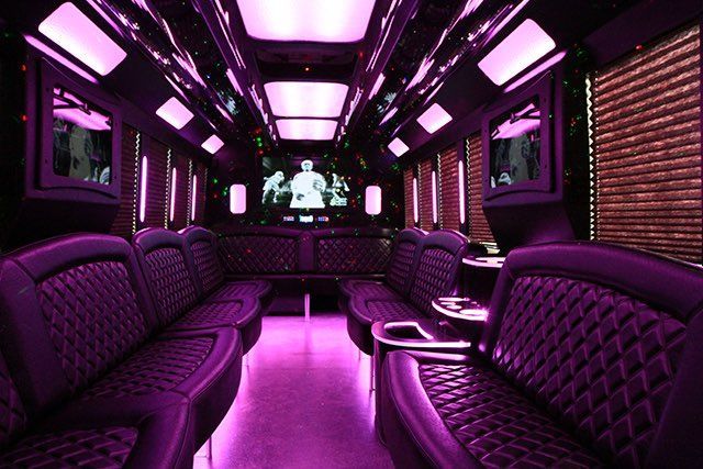 The inside of a limousine rental in Orange County with purple seats and a television.