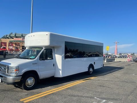 A white party bus rental in Orange County is parked in a parking lot.