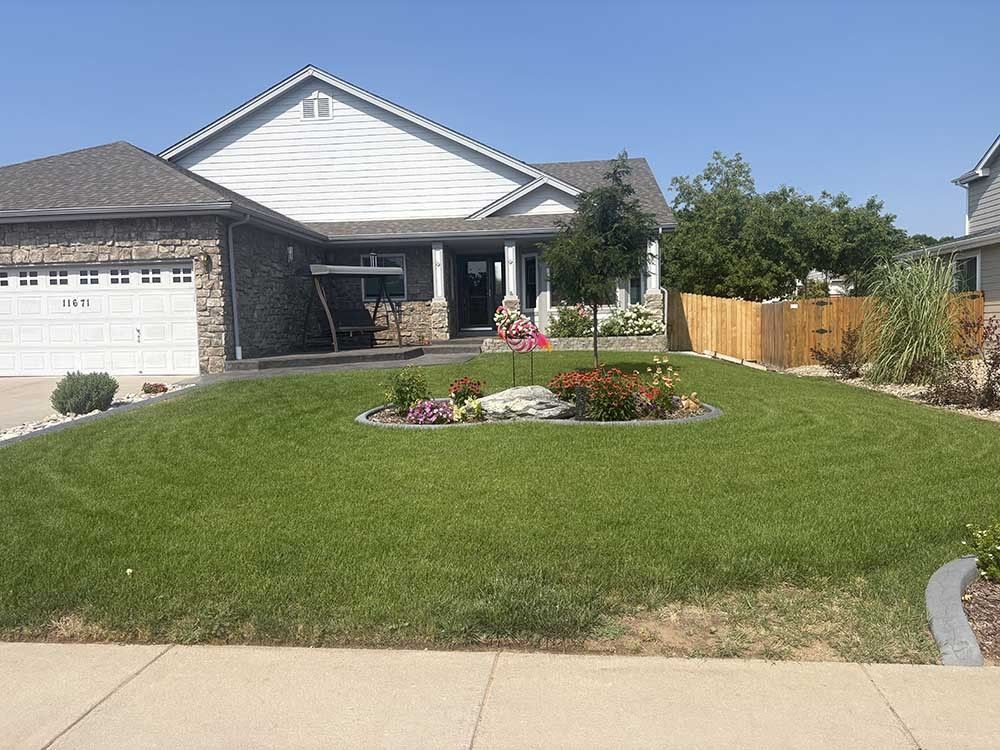 A single-story suburban house with a brick and light siding exterior, a front garage, and a circular garden bed in the lawn.