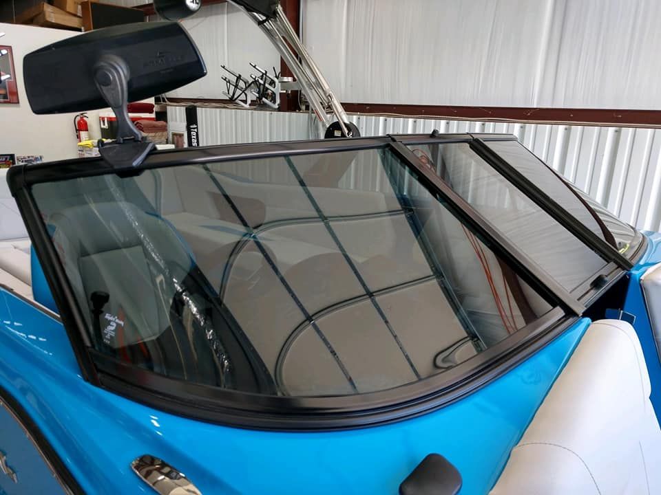 Blue boat windshield with black trim; driver's side mirror visible.