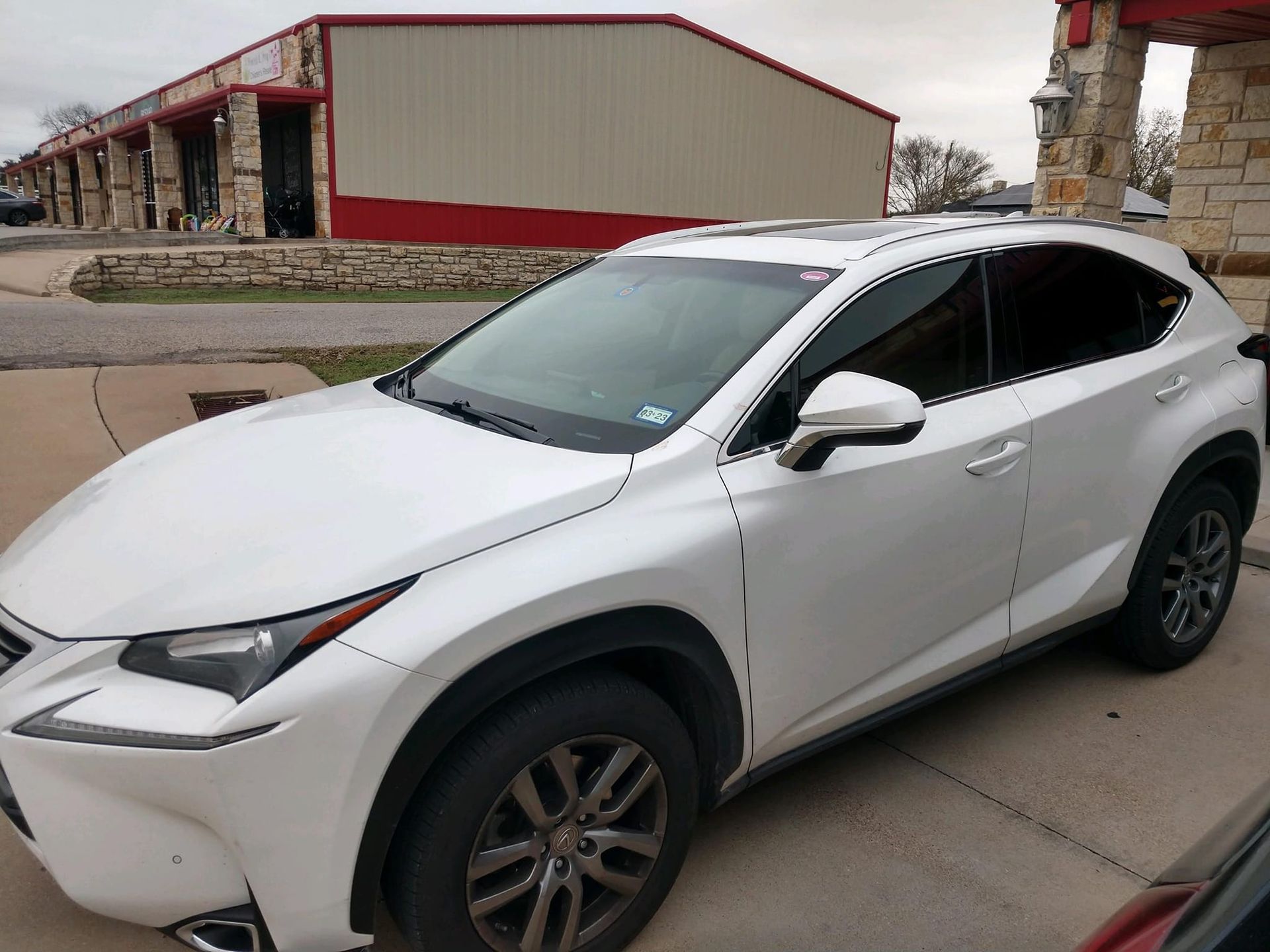 White Lexus SUV parked in front of a building with red and tan walls.