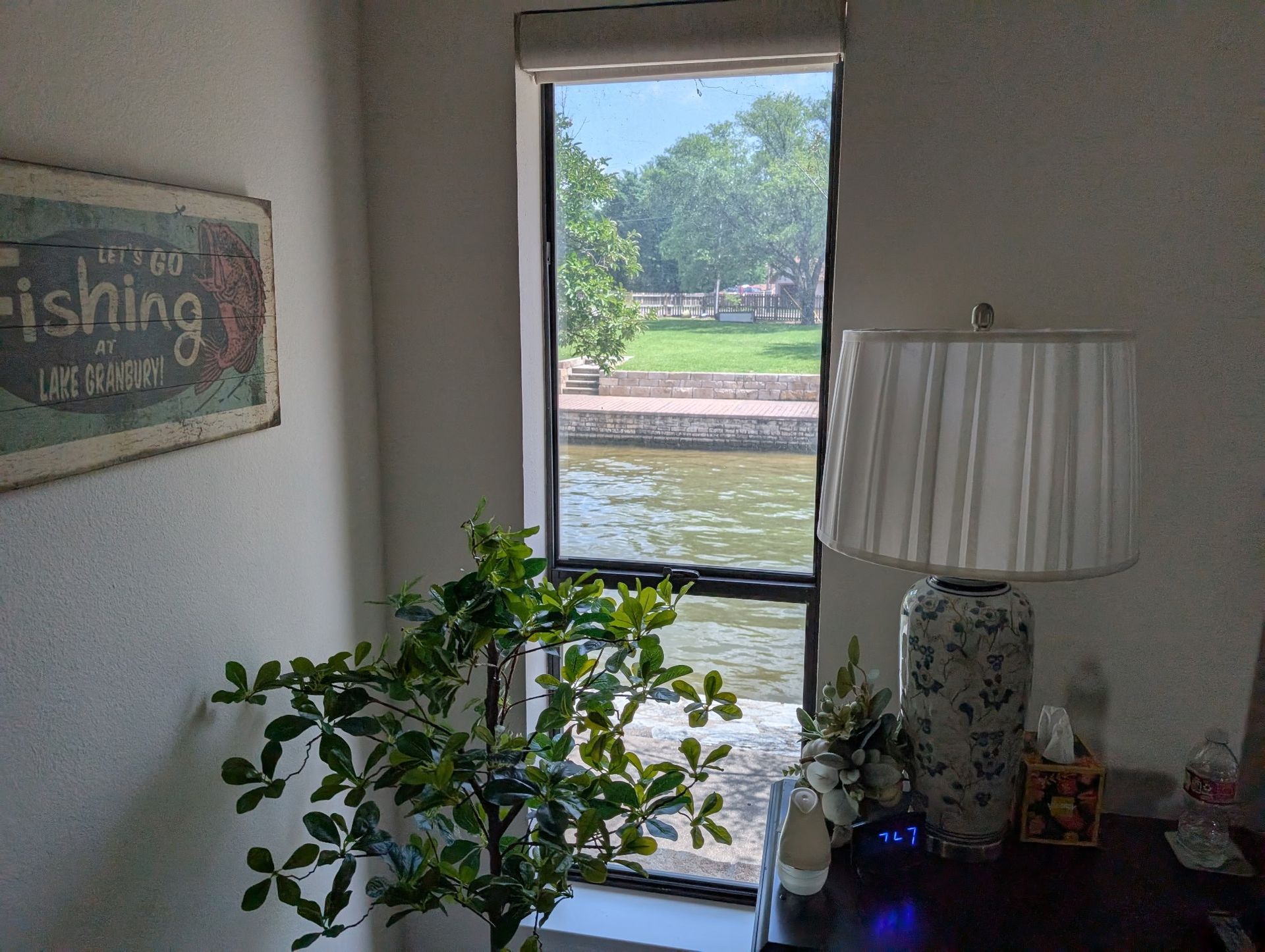 Interior view with a lake visible through a window. Features a lamp, a plant, and a 