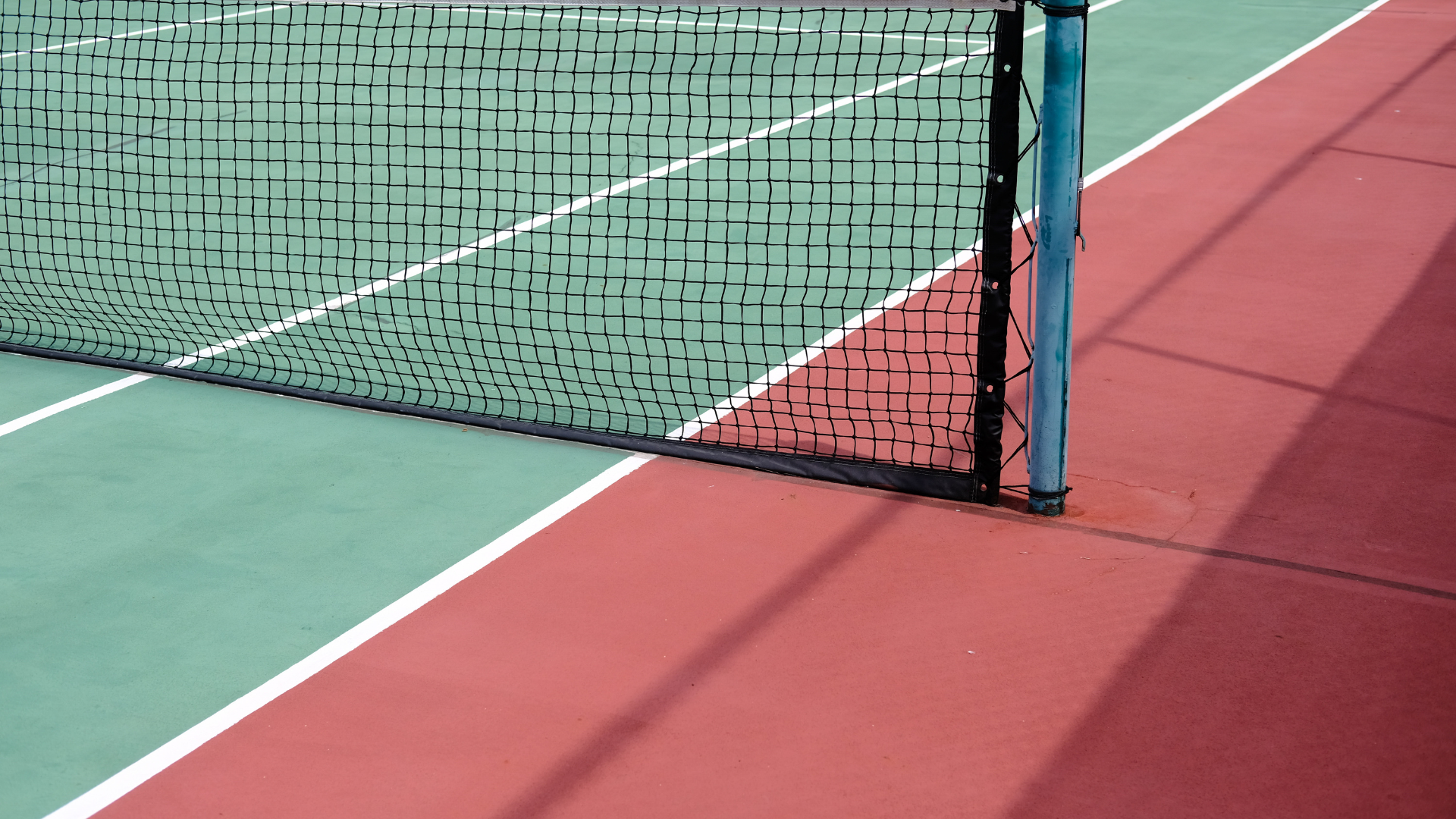 Tennis court net on a green and red hard court surface