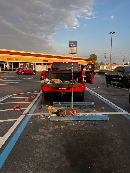 Red truck parked in a disabled parking spot, doors open. Tools and debris on the ground.