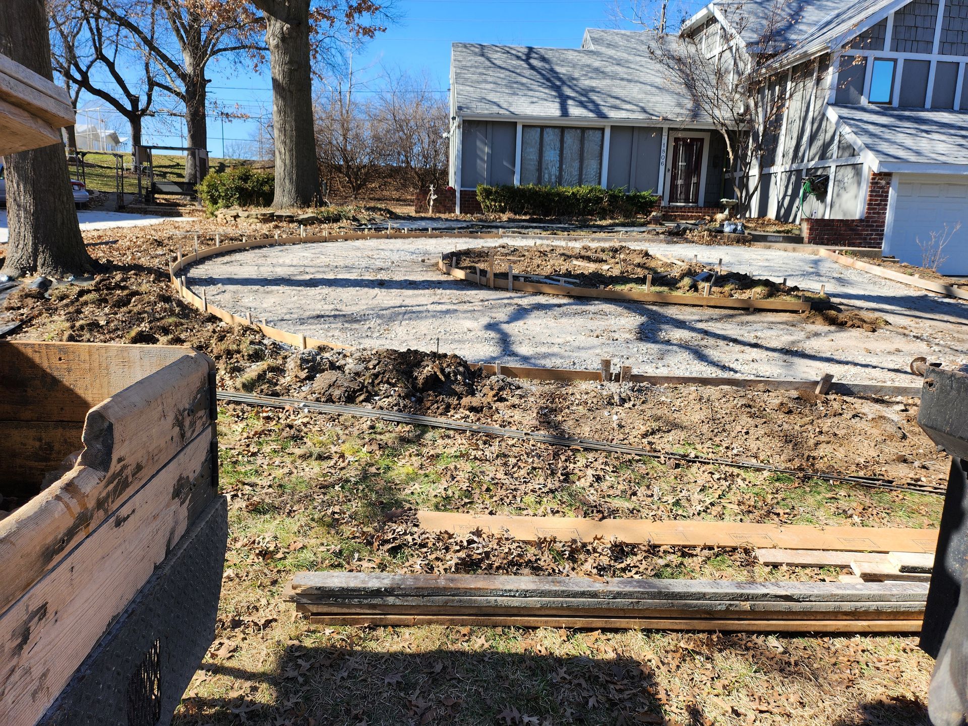 A concrete driveway is being built in front of a house.