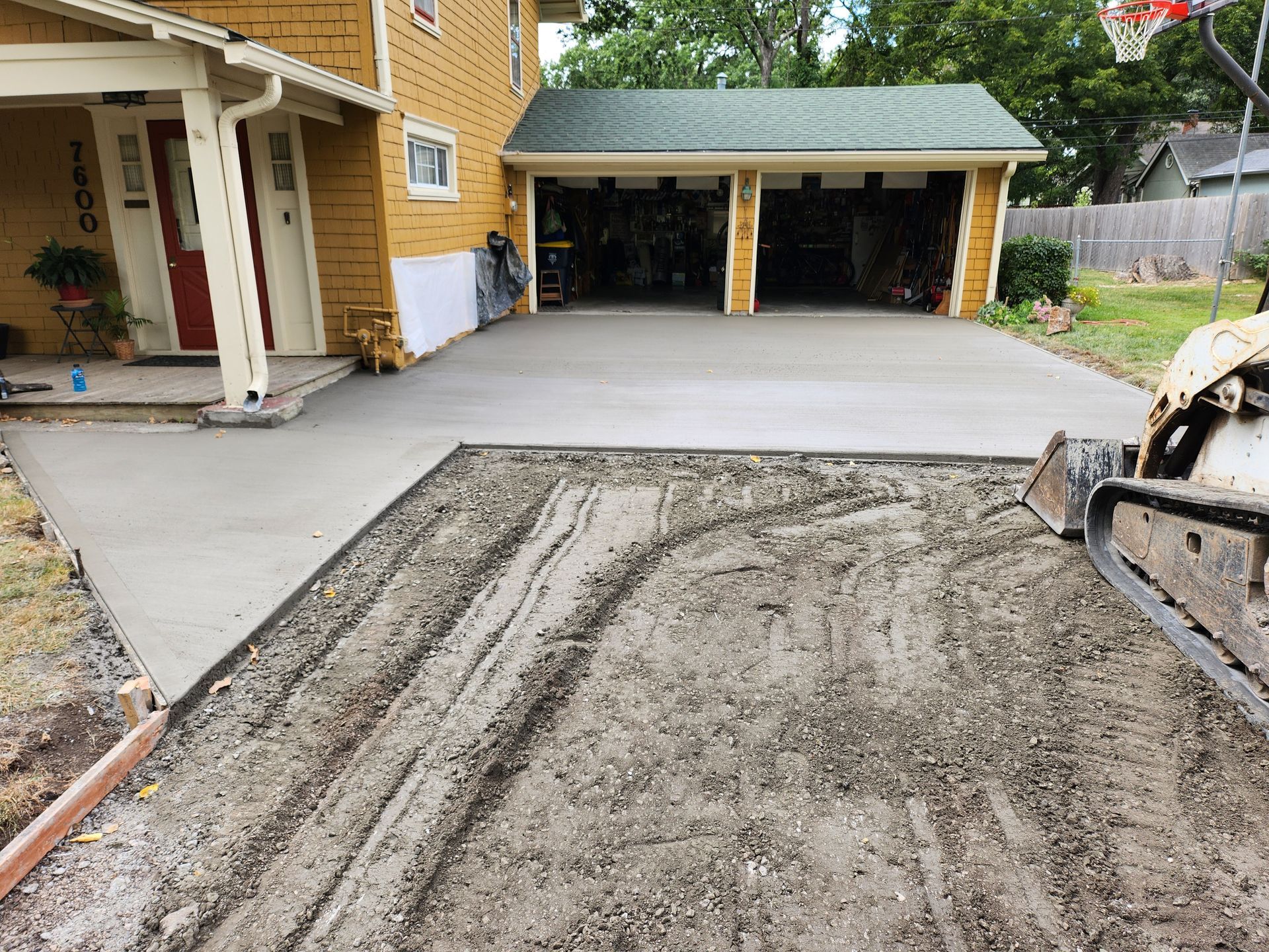 A concrete driveway is being built in front of a house.