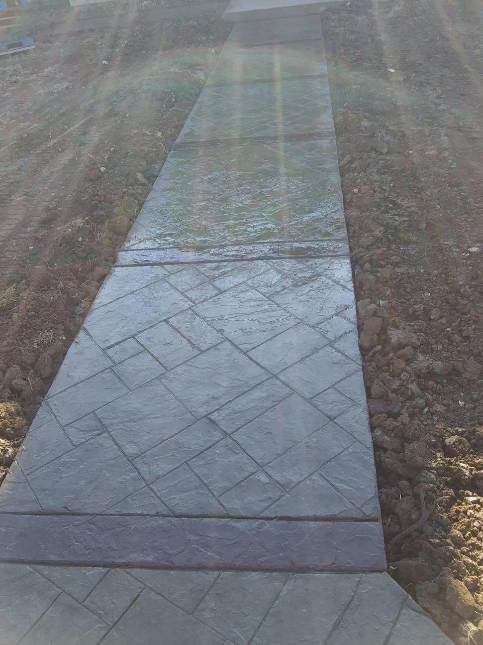 A concrete walkway with a pattern on it is going through a field.