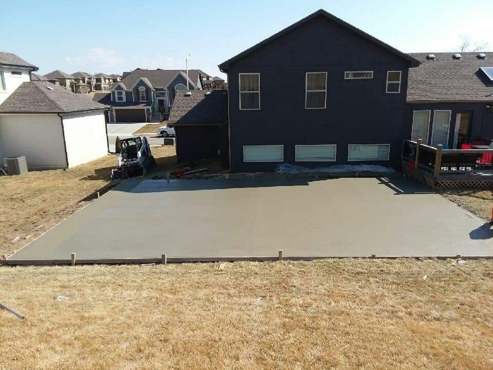 A large black house with a concrete driveway in front of it